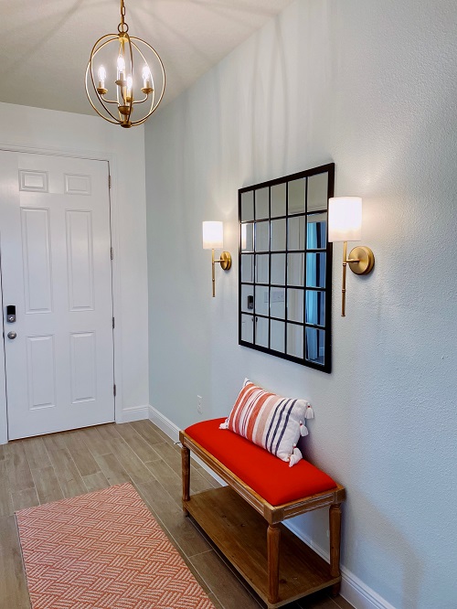 Entryway with coloful bench, mirror and sconces