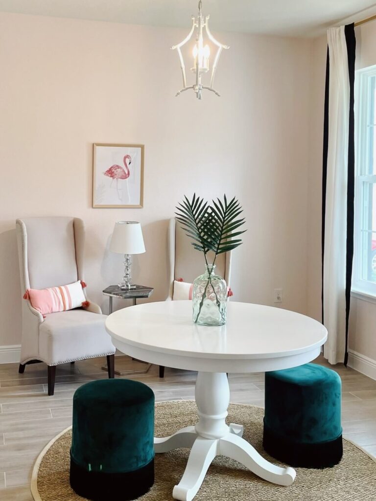 Pink sitting room with white table and green stools