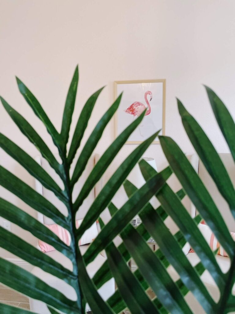 Faux palm leaves in front of flamingo wall art