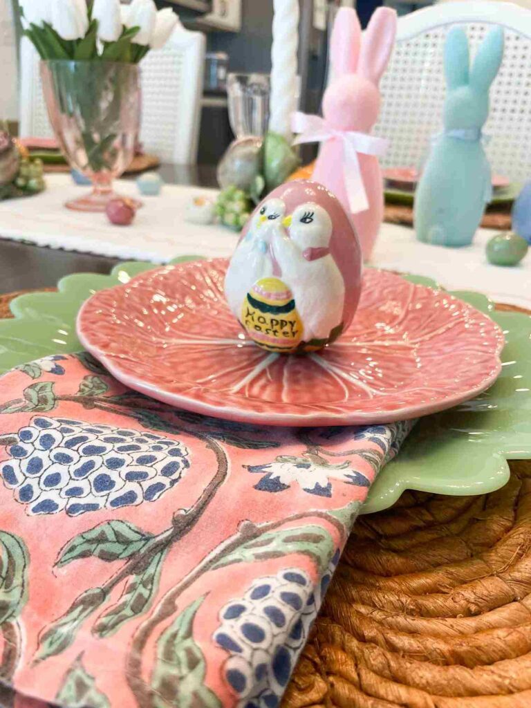 Close up of a ceramic Easter egg on a pink and green plate with a floral napkin